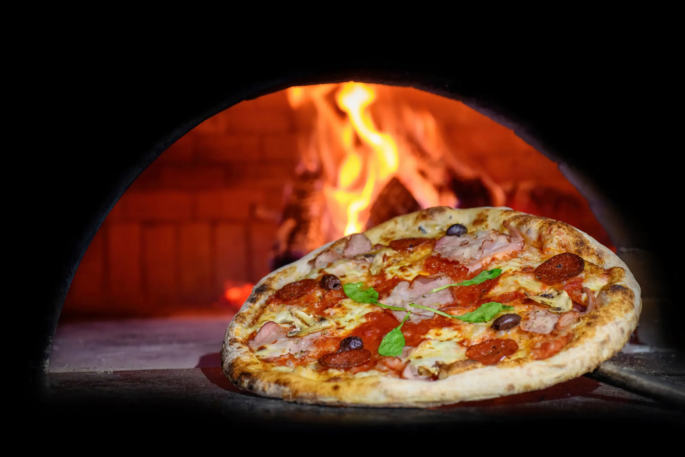 Horno de leña con una pizza en primer plano